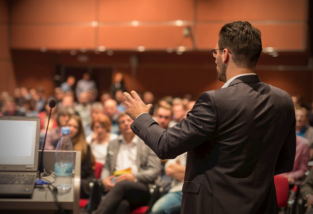 High value man delivering presentation to crowd 