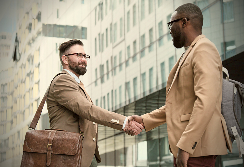 Two men in suits shaking hands in the street