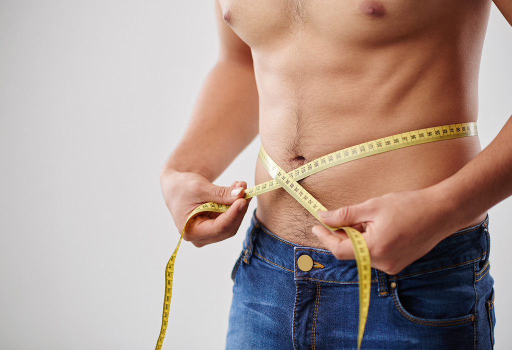 man in jeans measuring his waist size