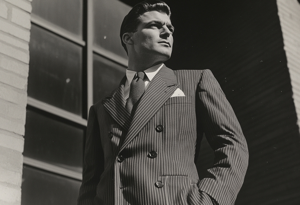 man wearing a drapey, 1940s style double-breasted dark gray pinstripe suit