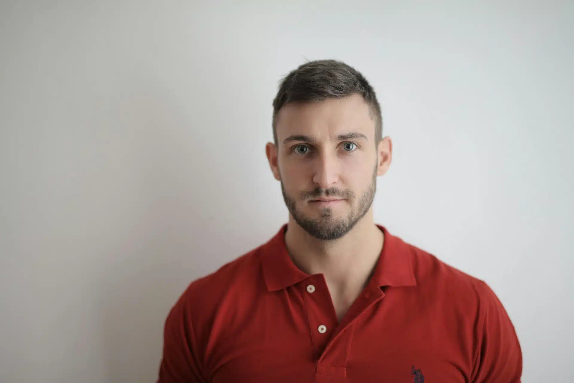 A handsome man wearing a red polo shirt.