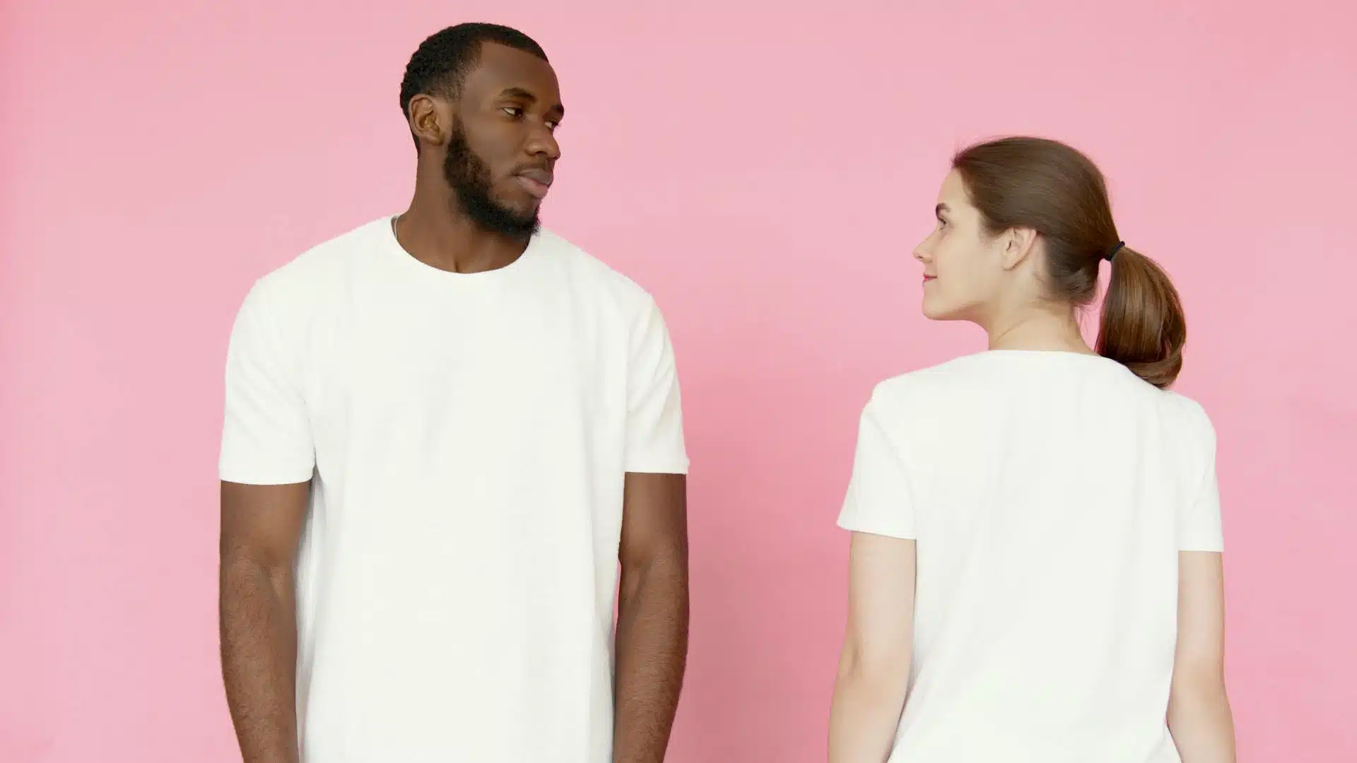 A man and a woman wearing white t-shirts looking at each other.
