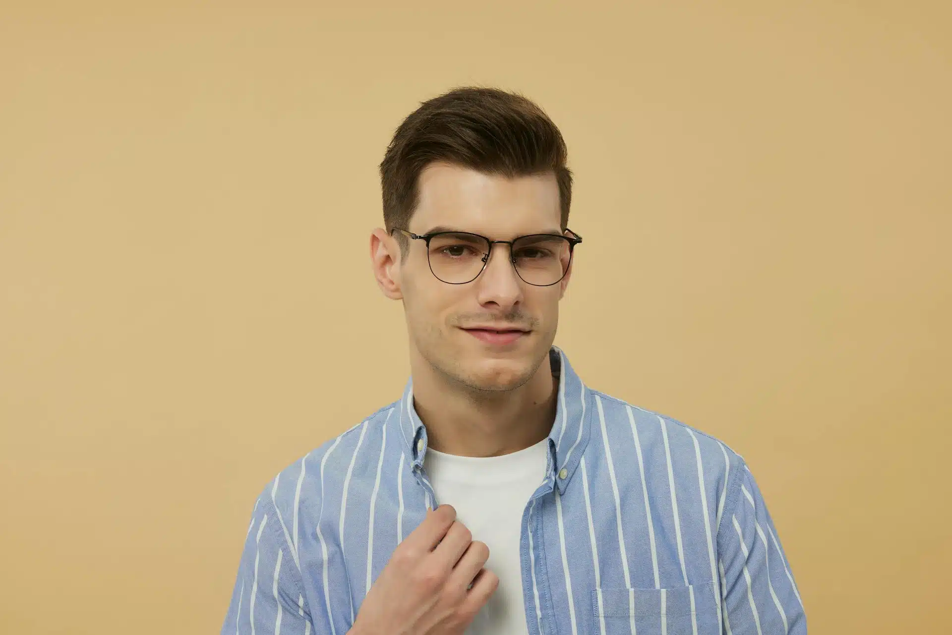 Man in glasses wearing a blue vertically striped shirt over a white t-shirt.