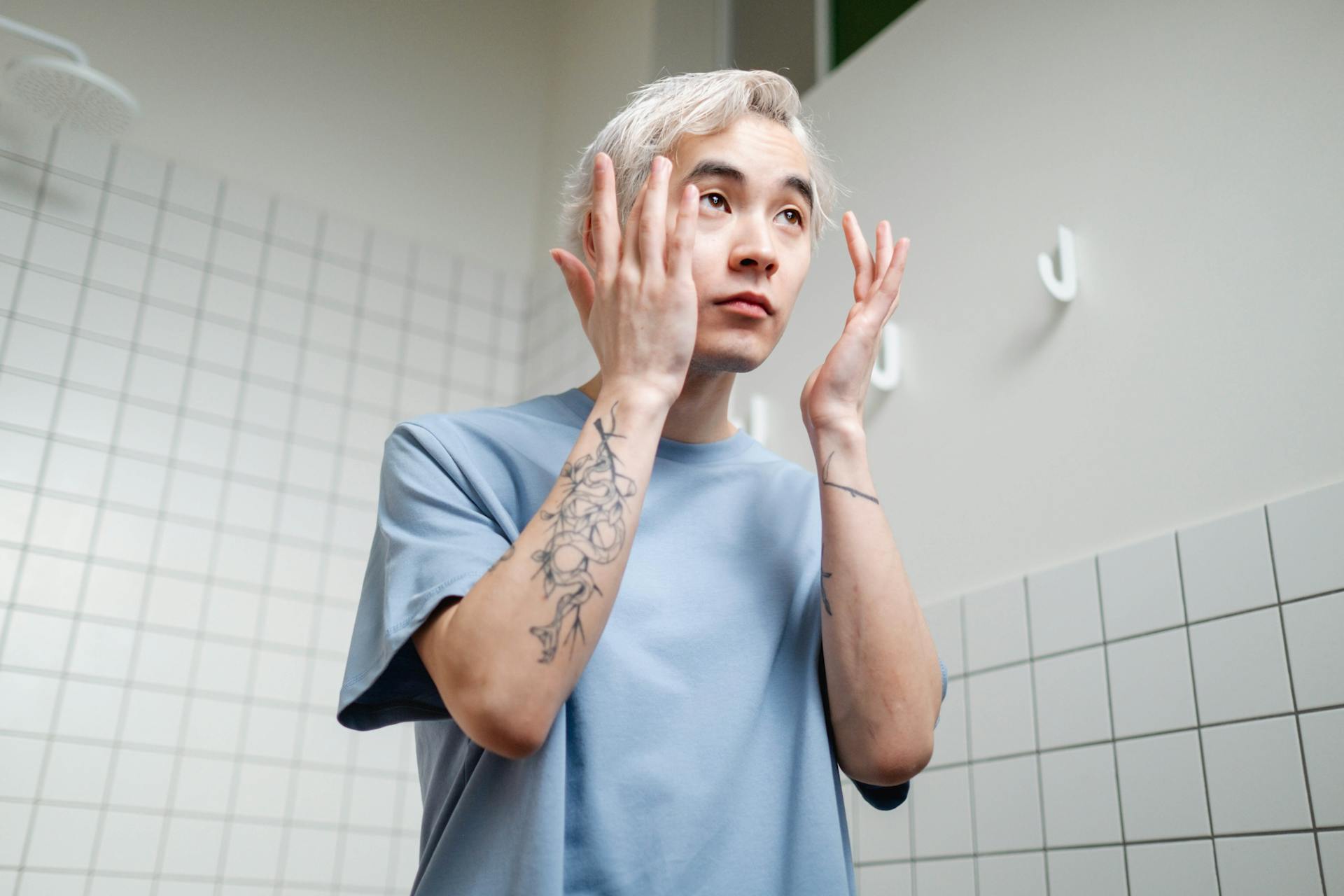 Man in Blue Crew Neck T-shirt Fixing His Eyebrows.