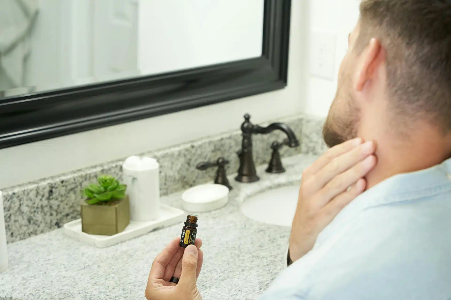 A man in a bathroom applying fragrance.