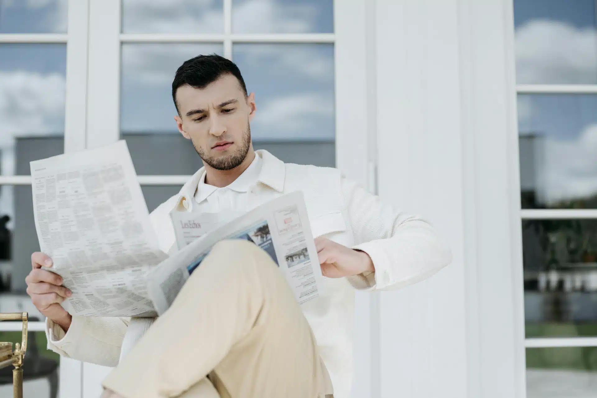 A man sitting on a chair reading newspaper.