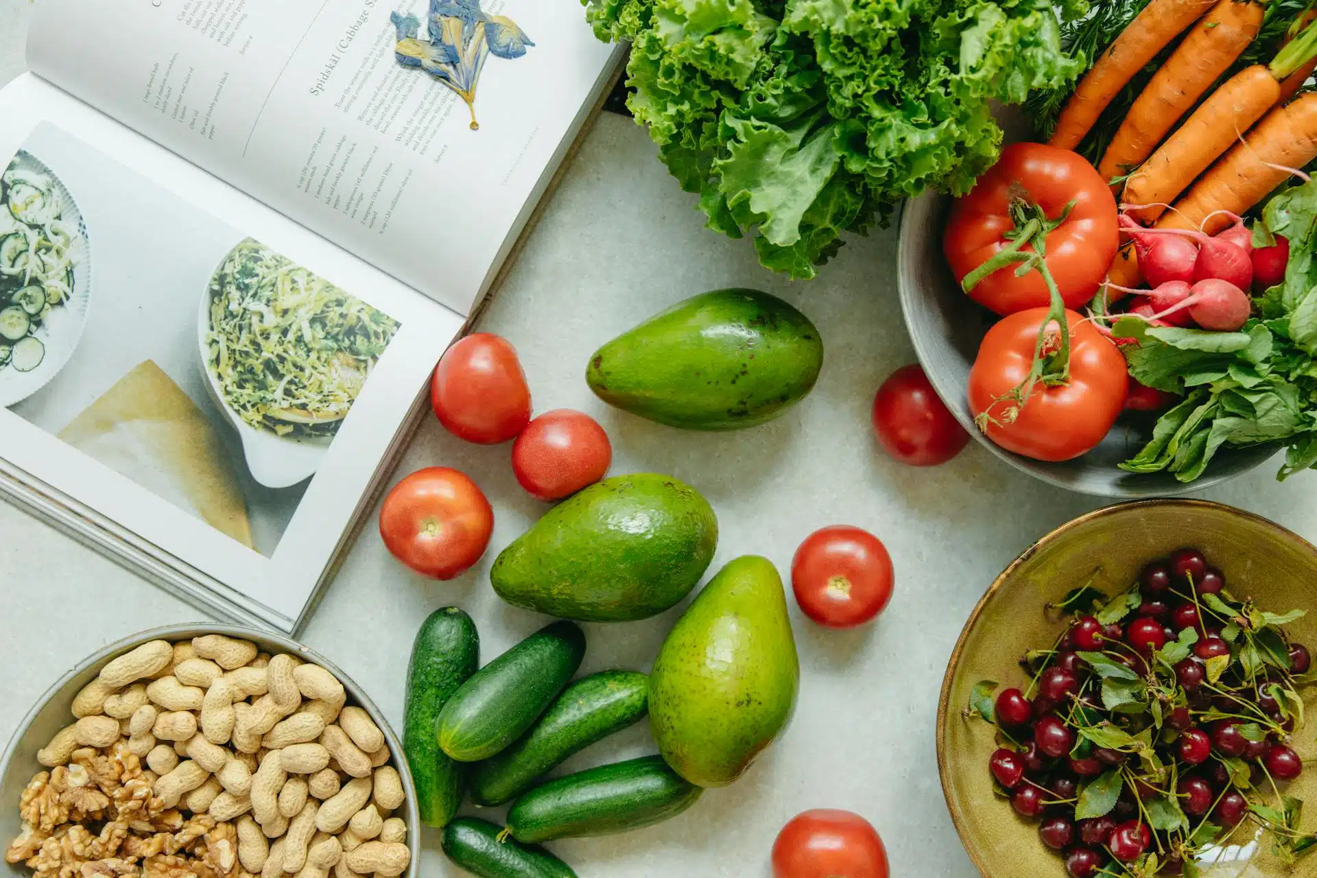A recipe book with fruits and vegetables around it.