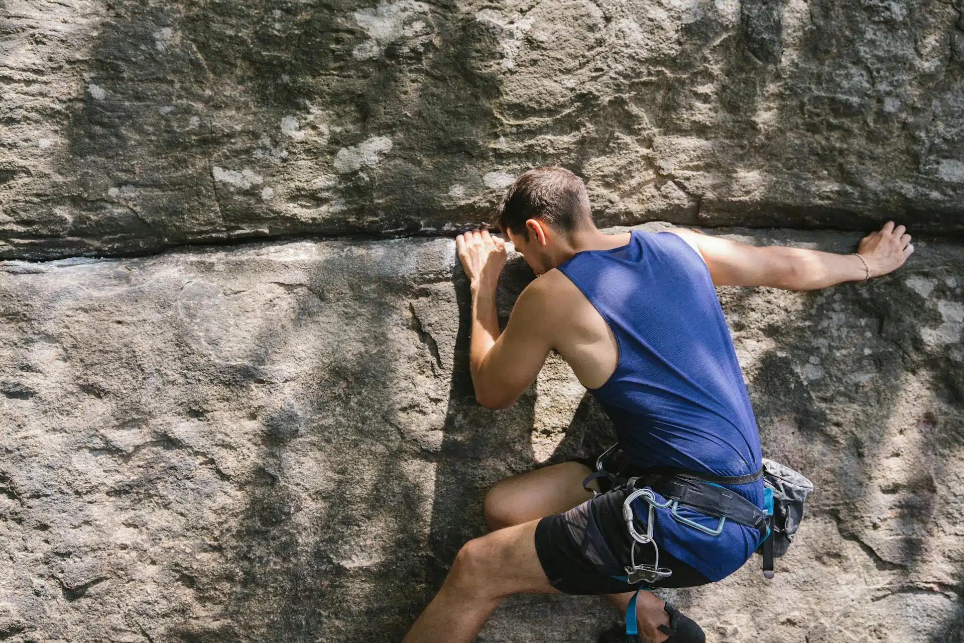 A man in blue gear rock climbing.