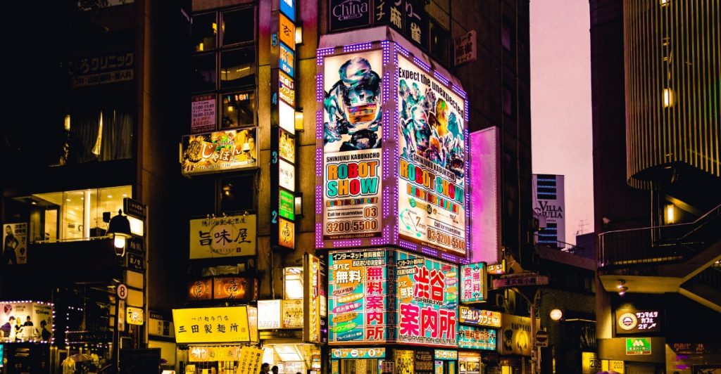 Busy street in Tokyo with digital signboards and pedestrians at night.