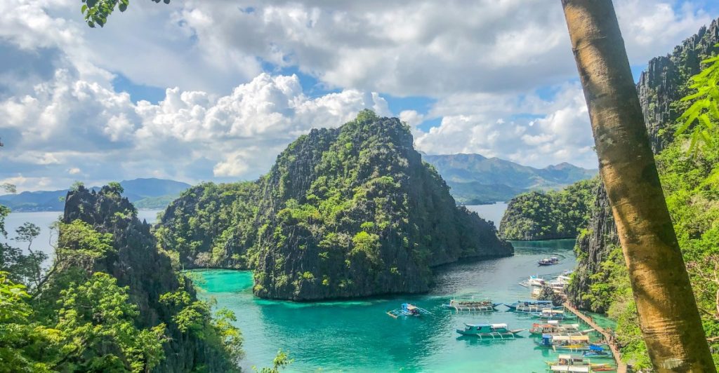 Aerial view of a tropical resort in the Philippines surrounded by crystal-clear water and lush green rocks.