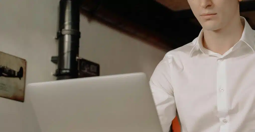 Close-up of a man in a white dress shirt working on a laptop computer.