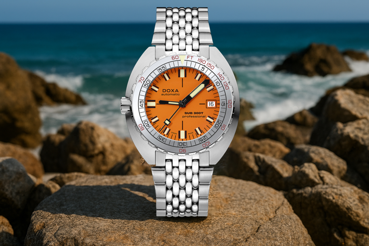 Doxa Sub 300T dive watch with a bold orange dial and silver case, placed on coastal rocks with waves crashing in the background