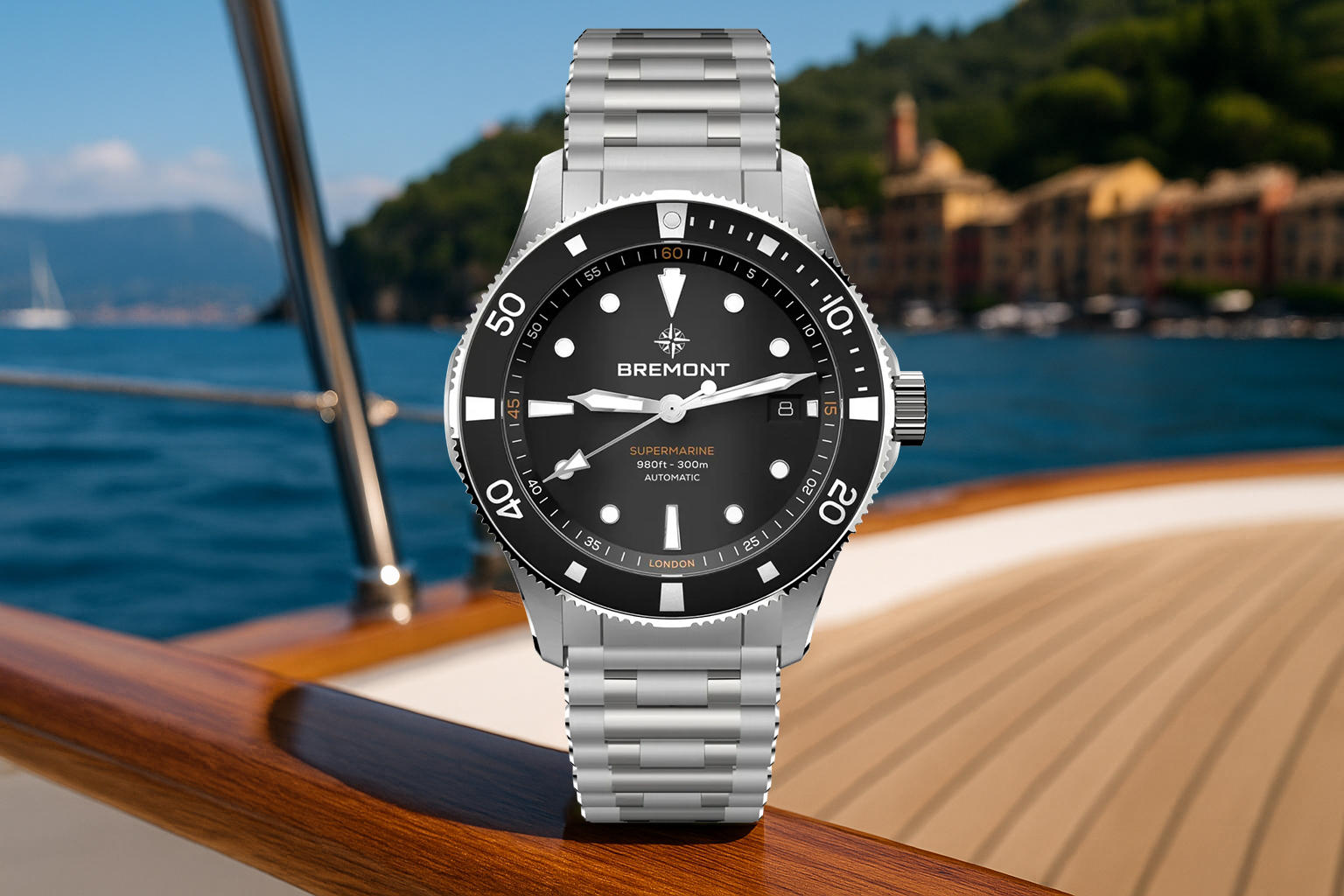Bremont Supermarine dive watch with a black dial and stainless steel bracelet, positioned on the deck of a luxury yacht with a scenic coastal town in the background