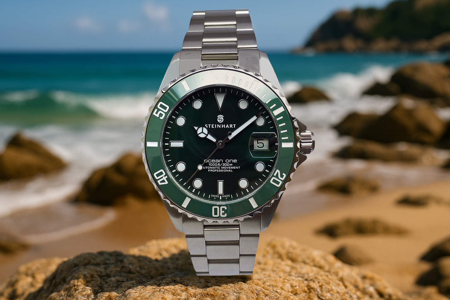Steinhart Ocean One dive watch with a green bezel and black dial, displayed on a coastal rock with waves and cliffs in the background