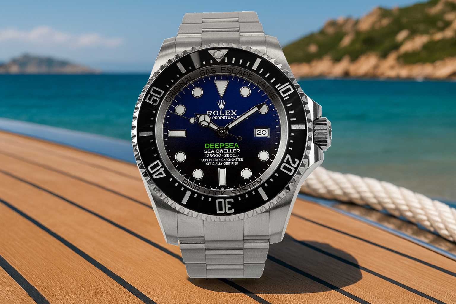 Rolex Deepsea Sea-Dweller dive watch with a blue-to-black gradient dial and stainless steel bracelet, placed on a yacht deck with turquoise sea and rugged coastline in the background