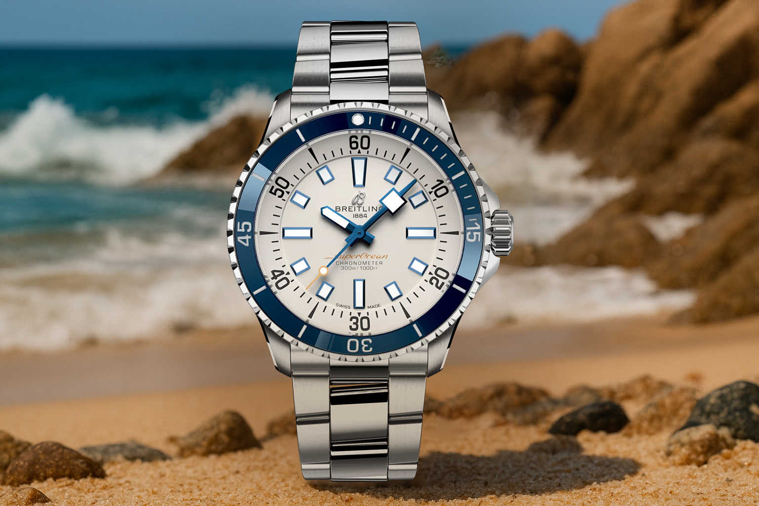 Breitling Superocean 42 dive watch with a white dial and blue bezel, placed on a sandy beach with waves crashing against coastal rocks