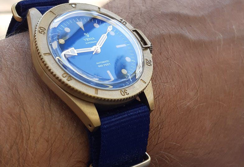 Yema Superman Bronze dive watch with a blue dial and NATO strap, worn on wrist and featuring the signature bezel-lock system