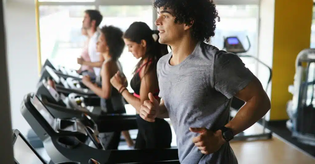 Several people running on treadmills in a gym setting.