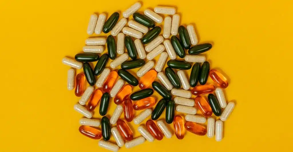 An assortment of vitamin capsules scattered on a bright yellow surface.