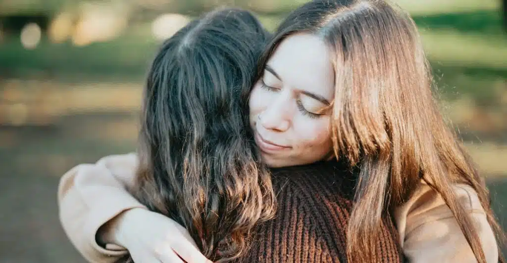 Two people embracing each other closely in an outdoor setting.