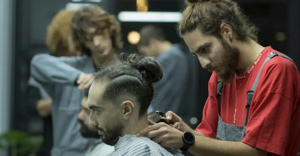 A barber cutting a customer's hair in a barbershop using an electric trimmer.