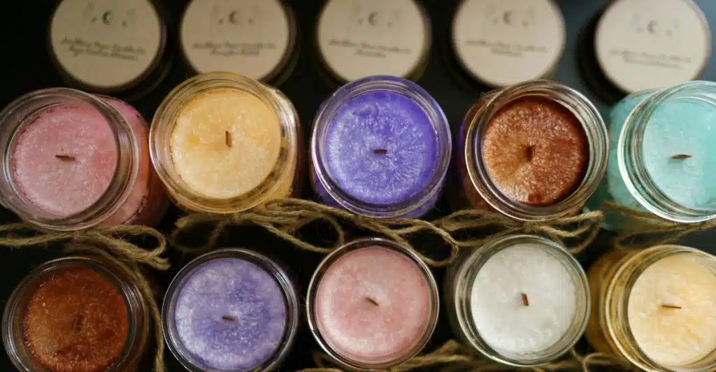 An overhead view of an assortment of colorful candles in jars, arranged on a surface.