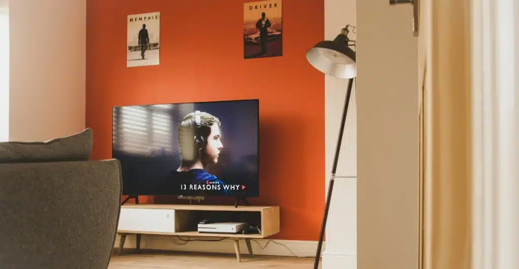 A TV placed in a living room setting, displaying the series "13 Reasons Why".