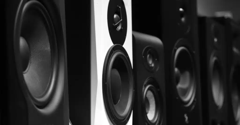 A close-up black and white image of various speaker drivers.