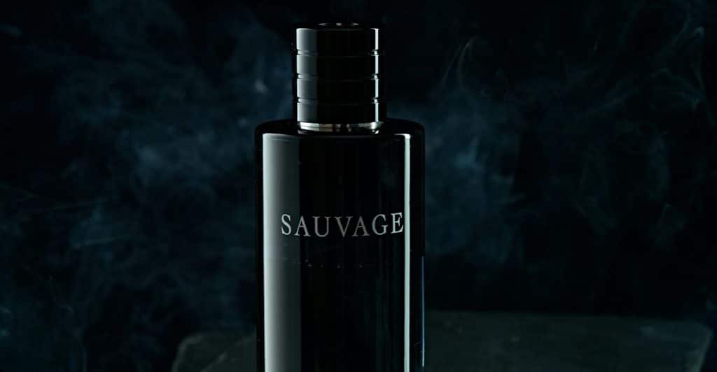 A Dior Sauvage Elixir fragrance bottle on a dark surface with smoke in the background.