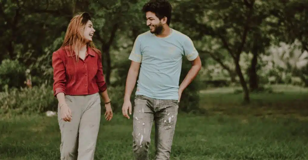 A man and woman walking and talking in a park.
