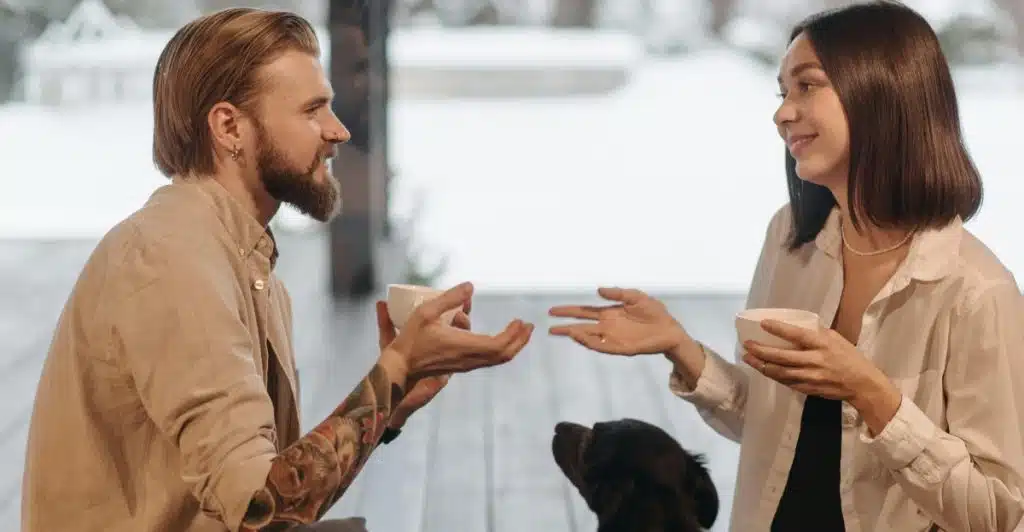A couple having a conversation with coffee cups in their hands.