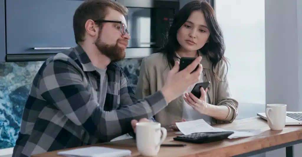A couple looking at a phone screen together at a table.