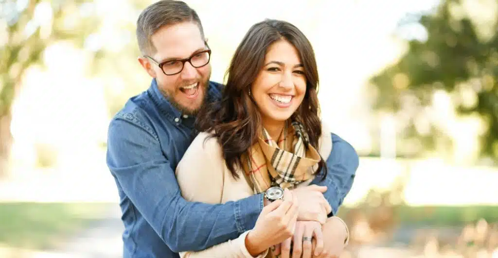 A couple hugging and smiling outdoors.