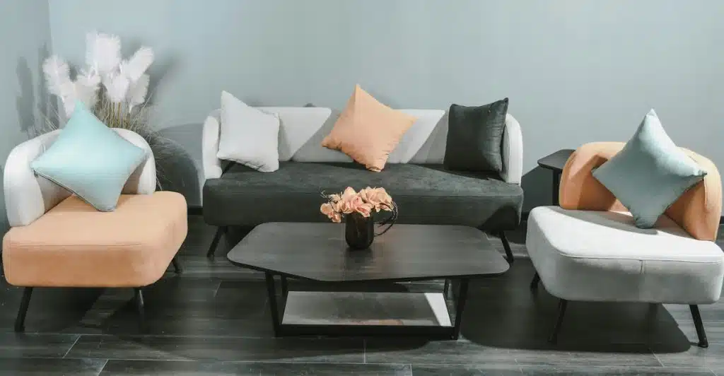 Modern living room furniture arrangement with artificial plants in the corner.