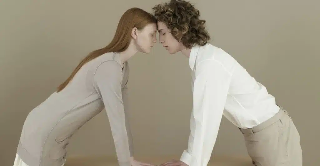 Two people standing close and touching foreheads, with their hands resting on a table.