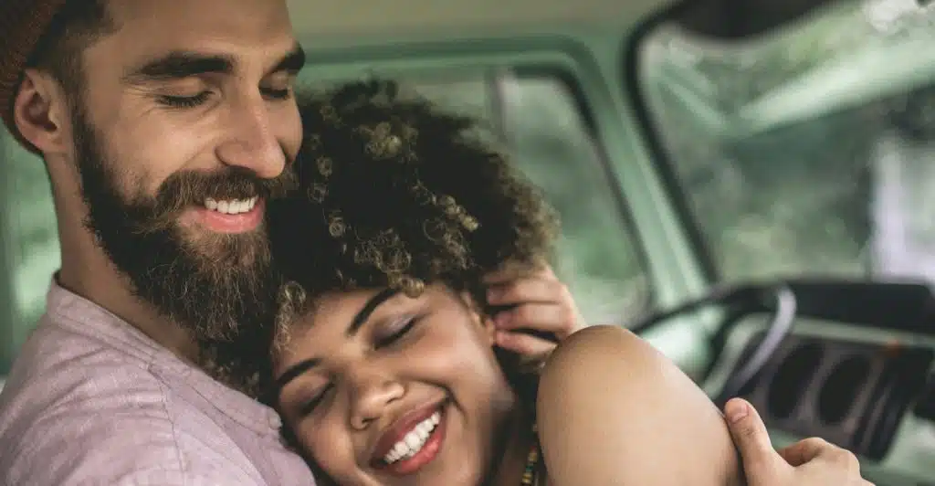 A couple hugging and smiling inside a vehicle.