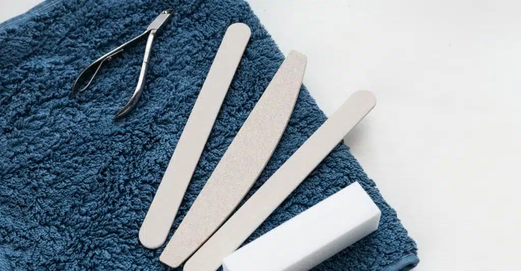 Nail clippers and several nail files arranged on a folded blue towel.