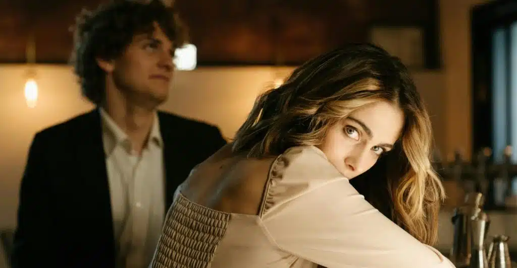 A woman looking over her shoulder while a man sits across the counter at a bar.