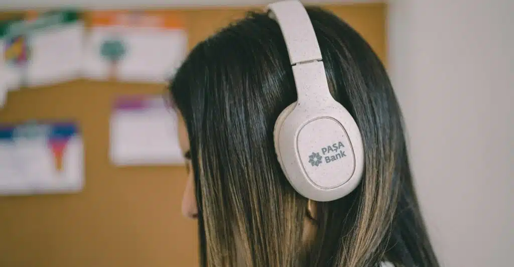 A woman with long hair wearing white noise-cancelling headphones that have a logo on the side.