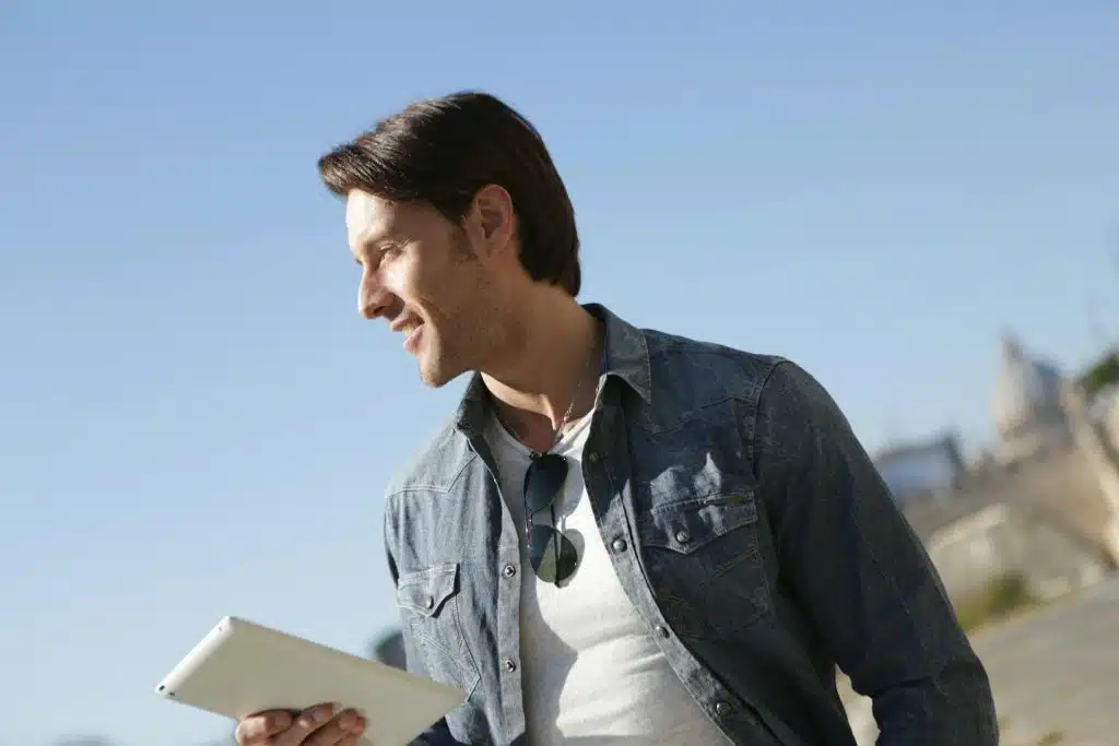 Man in Denim Jacket Holding White Tablet