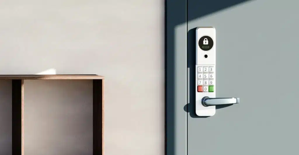 A white smart door lock with a keypad on a gray door.