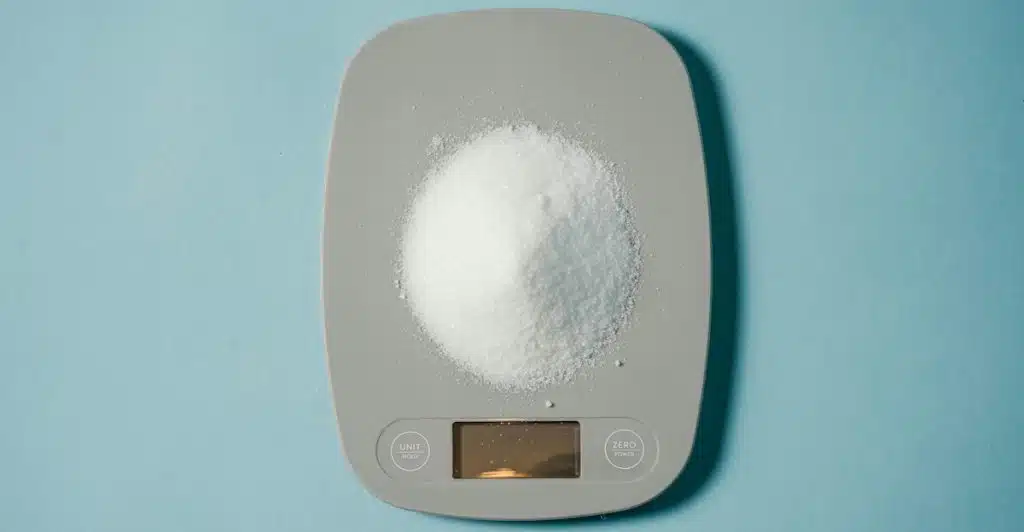 A gray smart kitchen scale with a pile of white powder on it.
