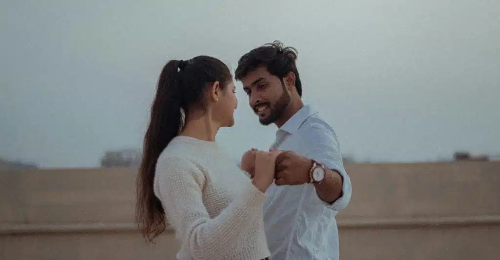 A man and a woman holding hands and looking into each other's eyes.