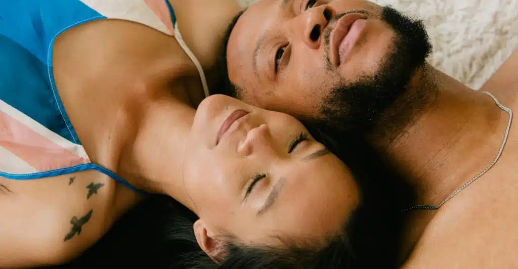 A man and a woman lying on a textured surface, with the woman's head resting on the man's shoulder