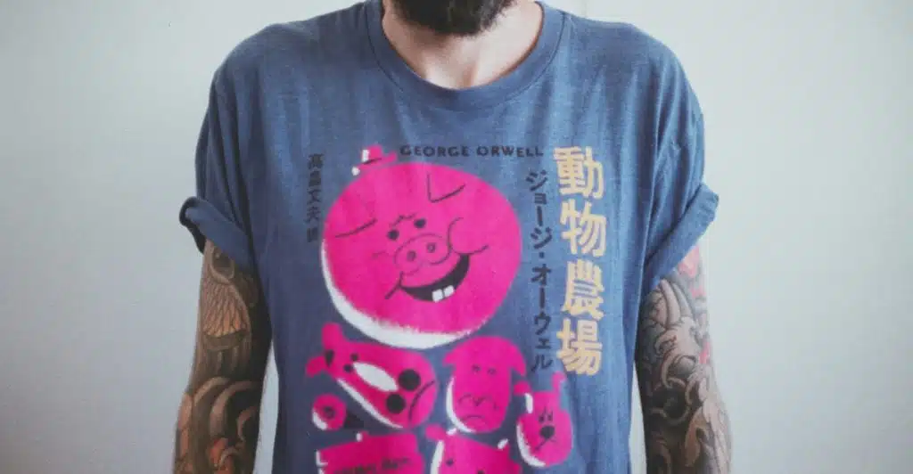 A man with a beard wearing a blue t-shirt with a large pink graphic print