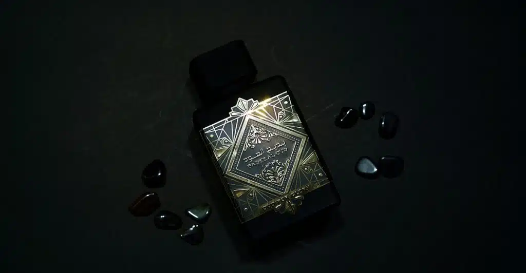 A Kilian Black Phantom fragrance bottle with ornate gold and silver designs, surrounded by small dark stones.