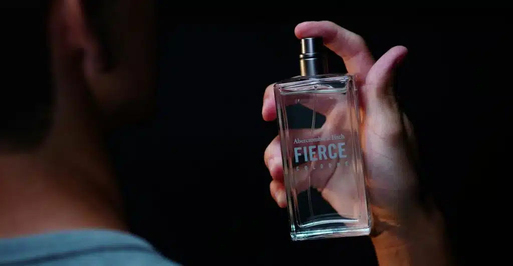 A man holding a bottle of Abercrombie & Fitch Fierce cologne.