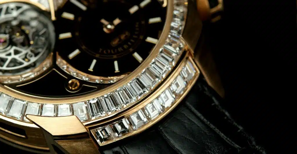 A close-up of a luxury watch featuring a black dial surrounded by baguette-cut diamonds and a gold-toned case.