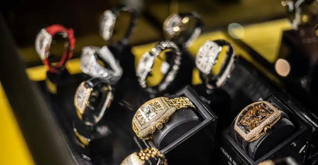 A display of multiple luxury watches with various designs, some adorned with jewels, showcased on individual stands.
