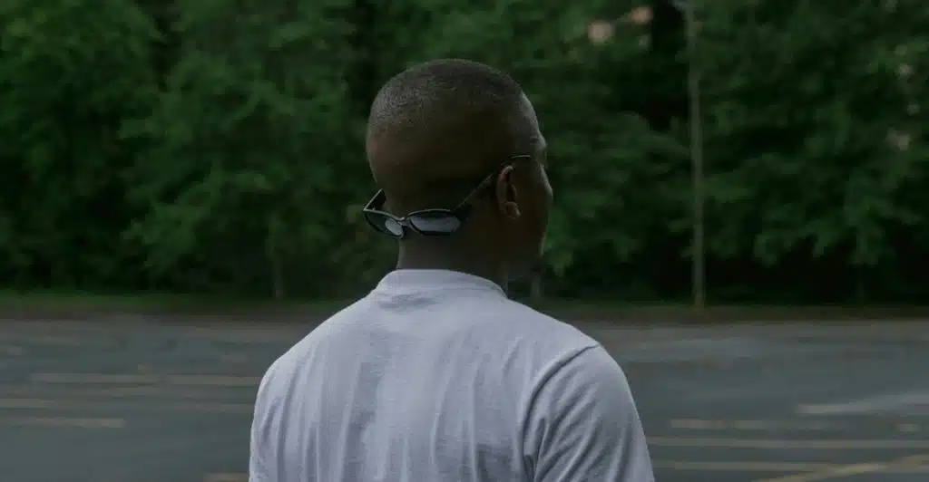 A man with a buzz cut wearing sunglasses on the back of his head, seen from behind.